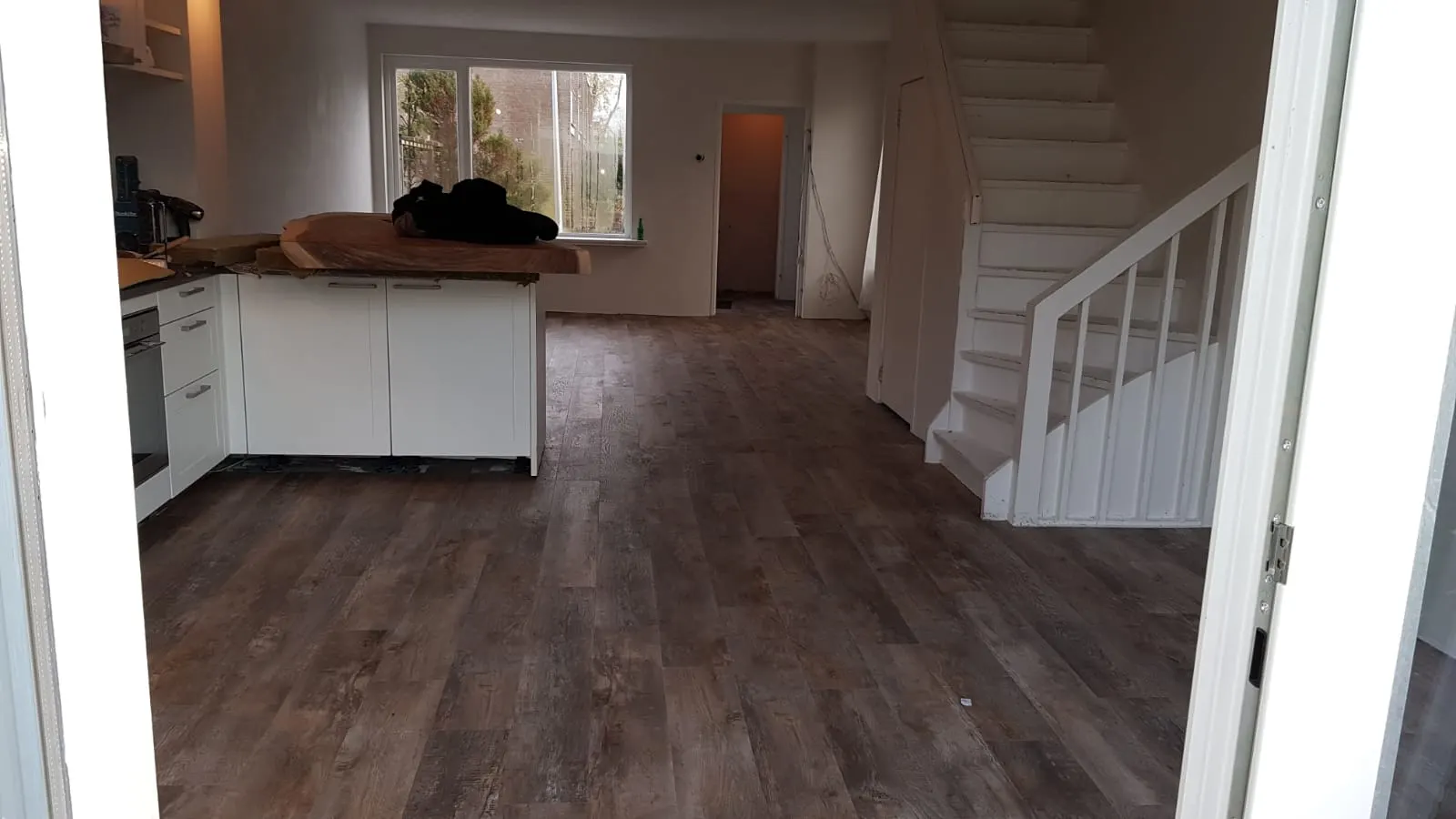 Donkere plankenvloer van keuken tot trap